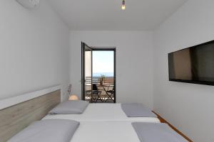 a white bedroom with a bed and a balcony at Luxury apartment Macola Free beach parking in Makarska