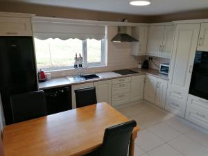 a kitchen with a wooden table and a black refrigerator at White Mountain Cottage in Newry
