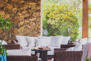 a patio with white couches and a stone wall at Hotel Aquadulci in Chia