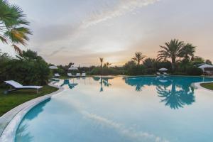 a pool at a resort with palm trees at Hotel Aquadulci in Chia