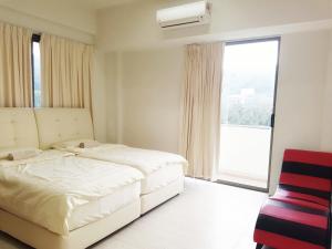 a white bedroom with a bed and a window at By The Sea Duplex Condo in Batu Ferringhi
