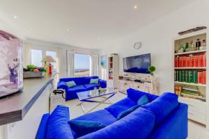 a living room with blue couches and a tv at Beachfront Apartment Migjorn Playa in Colònia de Sant Jordi