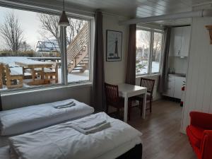 a room with two beds and a table and a balcony at Lofoten Bed & Breakfast Reine - Rooms & Apartments in Reine