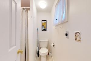 a white bathroom with a toilet and a window at Loon Nest in Rockwood