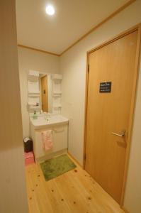ein Badezimmer mit Waschbecken und eine Tür mit Schild drauf in der Unterkunft Guesthouse Arakura in Fujiyoshida