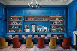 une bibliothèque bleue avec des chaises et des étagères dans l'établissement Kimpton Charlotte Square by IHG, à Édimbourg
