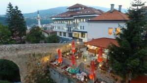 Blick auf ein Gebäude mit Sonnenschirmen und Tischen in der Unterkunft Hotel Vezir Palace in Travnik