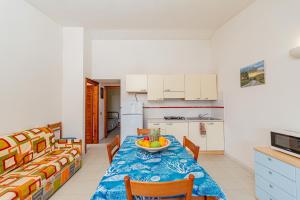 una cucina e un tavolo con un cesto di frutta di Appartamento Trilocale Le Canne 6 posti letto con giardino a San Teodoro