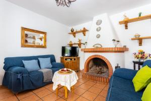 sala de estar con 2 sofás azules y chimenea en Cortijo Torrox Escape, en Torrox
