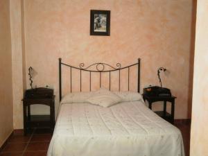 a bed in a bedroom with two nightstands and two tables at Hostal El Olmo in Camarena de la Sierra