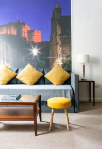 a living room with a couch and a yellow stool at Stewart by Heeton Concept - Aparthotel Edinburgh in Edinburgh
