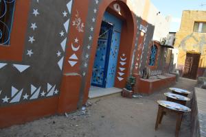 un edificio con una puerta azul y algunas sillas delante en Om-Abdallah, en Asuán