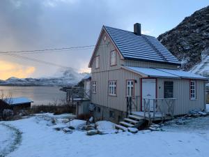 a house in the snow next to a mountain at Holiday home by Ryten in Fredvang