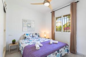 a bedroom with a bed with a purple blanket and a window at Apartamento Montesol 80 in Torrox Costa