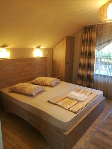 a bedroom with a large bed with two pillows at Pensiunea Dely_Cios in Vălenii de Munte