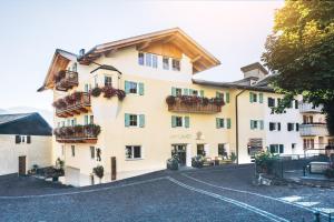 Un grand bâtiment blanc avec des fleurs sur les balcons dans l'établissement Zum Löwen-Post, à Trodena