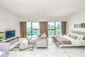 a white bedroom with a large bed and a tv at Modern Large Studio Central Park DIFC in Dubai