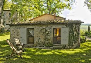 an old stone house with a chair in the yard at Casa Dell'Ambasciatore in Vivo dʼOrcia
