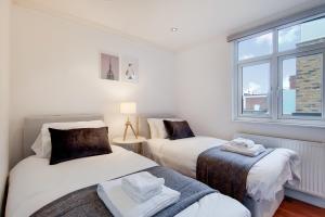 two twin beds in a room with a window at WelcomeStay Tooting Broadway 3 Bedroom Apartment in London