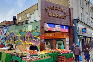 a market with a fruit stand in front of a building at WelcomeStay Tooting Broadway 3 Bedroom Apartment in London