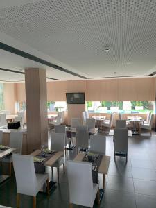 une salle à manger avec des tables, des chaises blanches et une télévision dans l'établissement Hotel Sercotel Plana Parc, à Alquerías del Niño Perdido