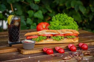 a sandwich on a wooden table with tomatoes and a drink at Pavlos Hotel in Kos Town
