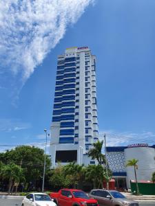 een hoog wit gebouw met auto's geparkeerd voor het bij Sea Light Hotel in Rach Gia