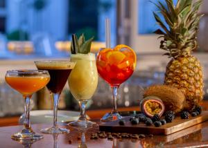 four wine glasses sitting on a table with drinks at Pavlos Hotel in Kos Town