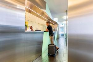 a man with a suitcase standing at a counter in an office at Hotel Cristal Design in Geneva