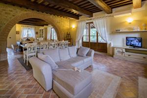 ein Wohnzimmer mit einem weißen Sofa und einem TV in der Unterkunft Villa dei Tramonti in Passignano sul Trasimeno