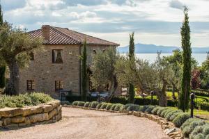 une maison en pierre avec des arbres et une allée en pierre dans l'établissement Villa dei Tramonti, à Passignano sul Trasimeno