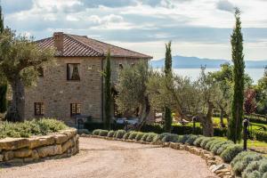 ein Steinhaus mit Bäumen und einer Steinzufahrt in der Unterkunft Villa dei Tramonti in Passignano sul Trasimeno