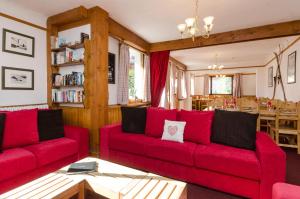 a living room with red couches and a dining room at Hotel Sylvana in Megève