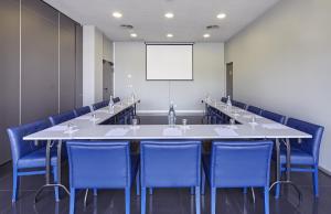 einen Konferenzraum mit einem großen Tisch und blauen Stühlen in der Unterkunft Holiday Inn Express Lisbon Alfragide, an IHG Hotel in Alfragide