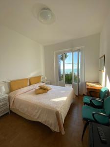 um quarto com uma cama, uma cadeira e uma janela em Appartamenti La Pineta em Marina dʼAndora