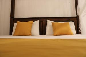 a bed with yellow pillows and a wooden headboard at Masith Guest House in Unawatuna