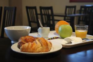 a table with a plate with a croissant and fruit on it at Orly Superior Hotel in Athis-Mons