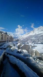 una ciudad cubierta de nieve con edificios y coches aparcados en Gîte de Fanfan en Barèges