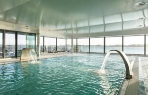 a swimming pool with water fountains in a building at Résidences Valdys Thalasso & Spa de Rockroum in Roscoff