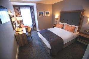 ein Hotelzimmer mit einem großen Bett und einem Schreibtisch in der Unterkunft Westlodge Hotel & Leisure Centre in Bantry