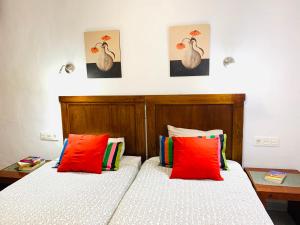 two beds in a bedroom with red and white pillows at Tagoror Lanzarote in Puerto del Carmen