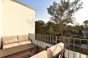a balcony with a couch and chairs on a balcony at SPA Penthouse Meerlust in Baabe