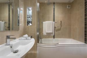 a bathroom with a sink and a bath tub and a mirror at Park Inn by Radisson Shannon Airport in Shannon