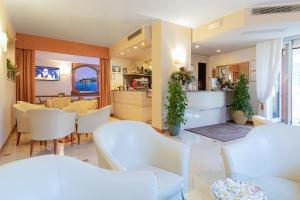 uma sala de estar com cadeiras brancas e uma mesa em Hotel GARDENIA & Villa CHARME Adults Friendly 10Plus em Bardolino