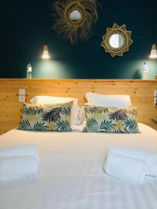 a bedroom with a white bed with two pillows at Hôtel Café Miramar in Le Grau-du-Roi