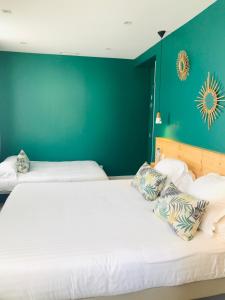 a bedroom with two beds and a green wall at Hôtel Café Miramar in Le Grau-du-Roi