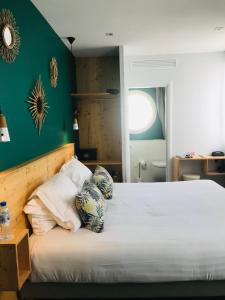 a bedroom with a large bed with green walls at Hôtel Café Miramar in Le Grau-du-Roi