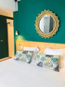 a bedroom with a bed with two pillows and a mirror at Hôtel Café Miramar in Le Grau-du-Roi