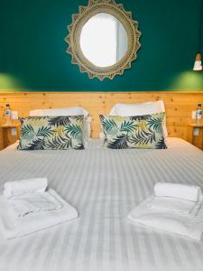 a large white bed with two pillows and a mirror at Hôtel Café Miramar in Le Grau-du-Roi