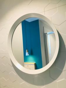 a round mirror on a wall with a blue wall at Hôtel Café Miramar in Le Grau-du-Roi